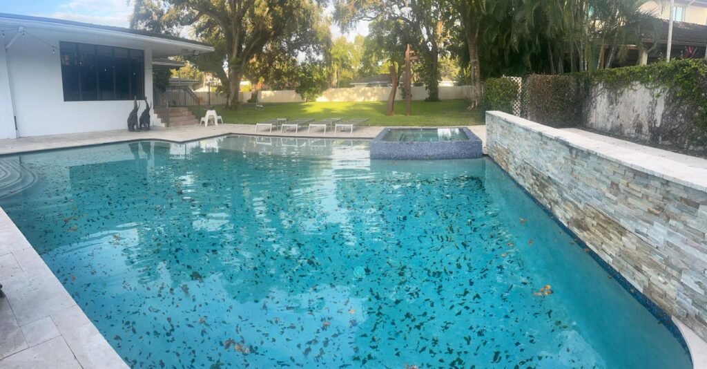 Piscina rectangular de patio trasero con el agua clara y el césped recién cortado al fondo